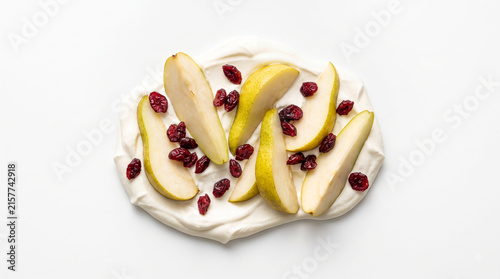 Distant shot of 5 to 10 autumn pear wedges and dried cranberries nestled on thick white maple sour cream