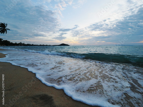 Foamy water at dusk with distant headland silhouette