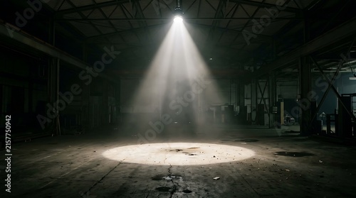 Bright spotlight shining down on the floor of a dark abandoned industrial warehouse