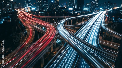 Night traffic light trails on a busy highway interchange in a modern city with skyscrapers