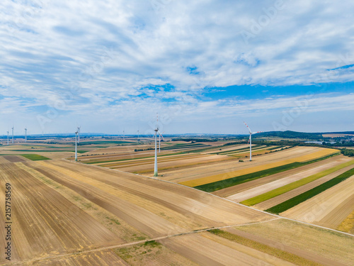 фотографія Wind turbines stand tall in a flat agricultural landscape under a blue sky with