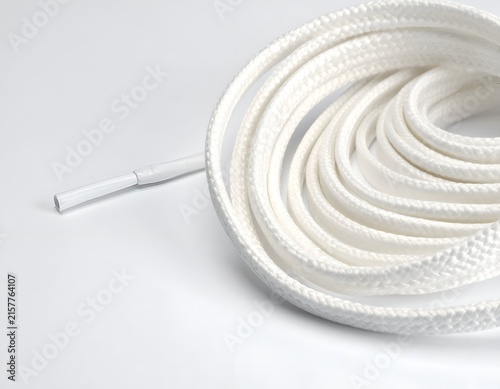 Coiled white shoelace on white background.