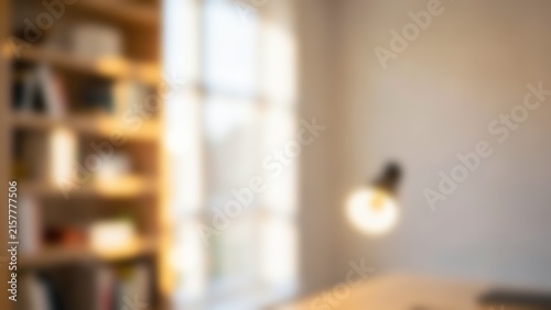 elegant blurred background of a warm sunny home office with wooden bookshelf and desk lamp ideal for virtual meeting backdrops or website hero banners