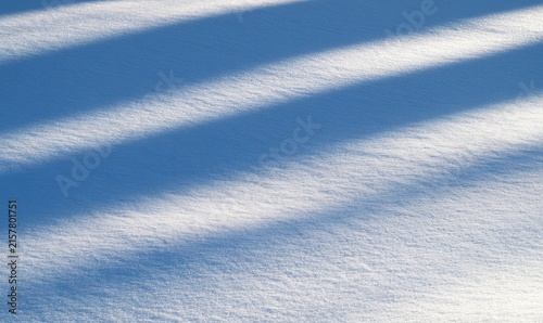 Crisp white snowfield textured by diagonal shadows cast by unseen objects