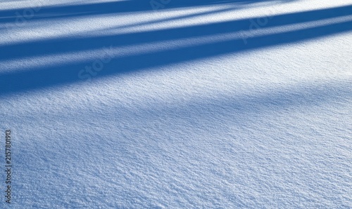 Crisp, textured snow surface with long, angular shadows cast across it