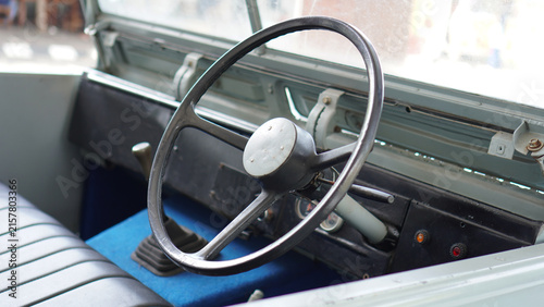 Detailed view of the steering area of ​​a classic Jeep, featuring a black steering wheel.