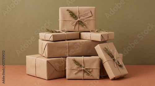Eco friendly Christmas shopping parcels wrapped in brown kraft paper with organic jute twine ribbon and fresh rosemary