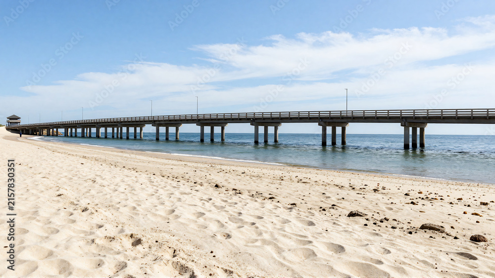 Fototapeta premium Long Concrete Bridge Over Sandy Beach and Blue Ocean