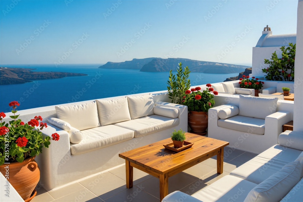 Fototapeta premium White terrace with outdoor furniture overlooks blue sea and islands. Comfortable seating area with cushions and wooden table. Red flowers in pots add color to this tranquil Greek island scene.