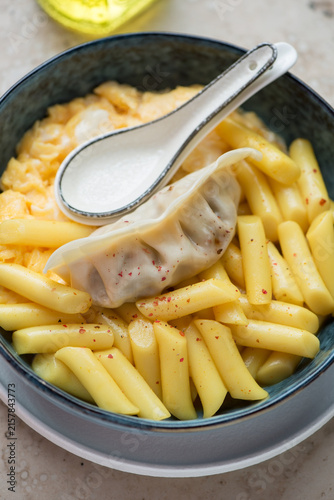 Cheesy korean tteokbokki or rice cakes with steamed egg and dumpling, vertical shot, close-up, selective focus