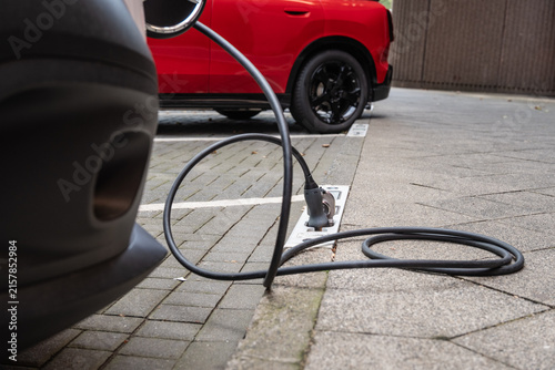 Ein E-Auto wird an einem Ladebordstein auf der KÖ mit einem Kabel aufgeladen, Düsseldorf, Deutschland