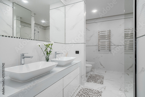 Foto Double vessel sinks on white vanity counter in marble tiled bathroom