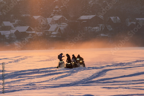 Obraz na plátne Group of people riding snowmobiles across a vast frozen field during a scenic wi