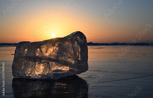 Konstfotografi A shiny transparent piece of ice on the frozen Lake Baikal at sunrise