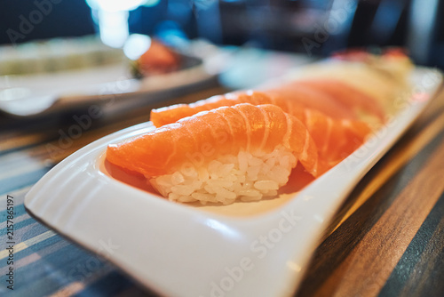 Salmon nigiri sushi on a white plate at a restaurant