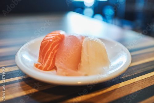 Three pieces of sashimi on a small round white plate