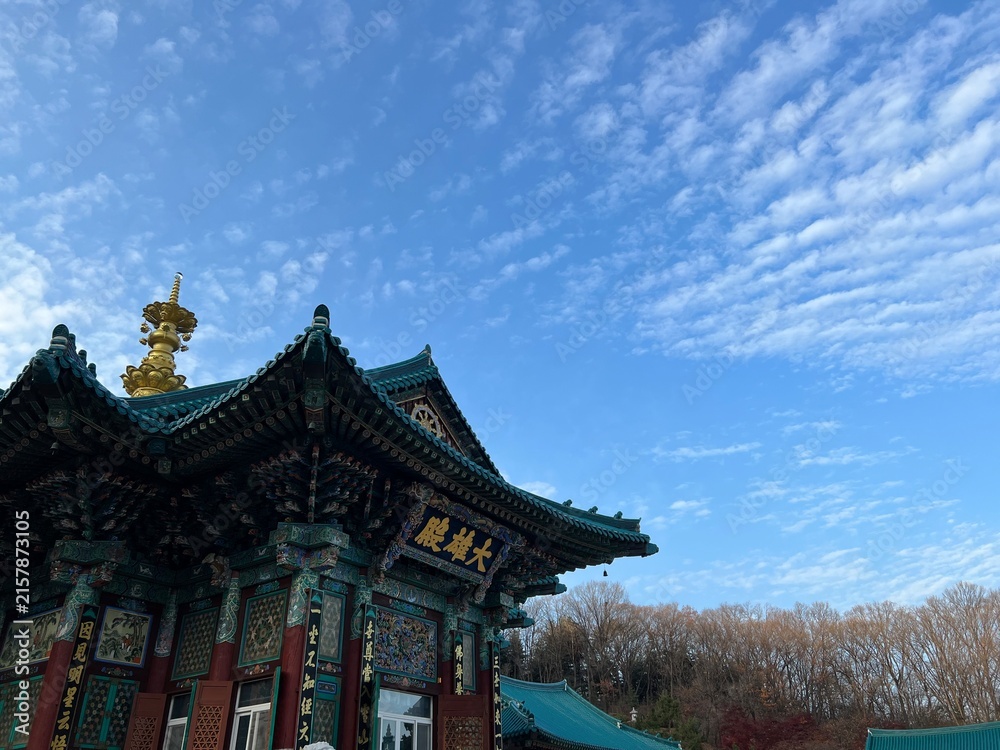Fototapeta premium 파란 하늘과 구름 아래 고즈넉하게 서 있는 한국 전통 사찰 대웅전