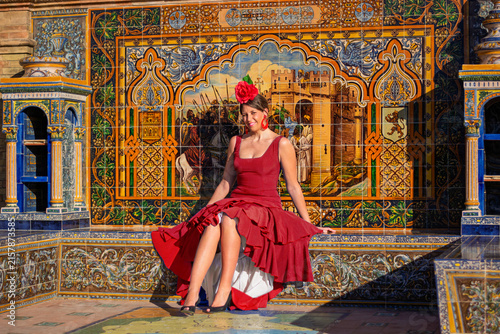 a beautiful girl in a flamenco dress sitting in front of the sun's rays