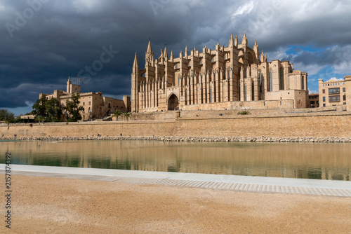 Cathedral of Santa Maria of Palma La Seu in Majorca Spain with Royal Palace of La Almudaina under dramatic thunderstorm clouds