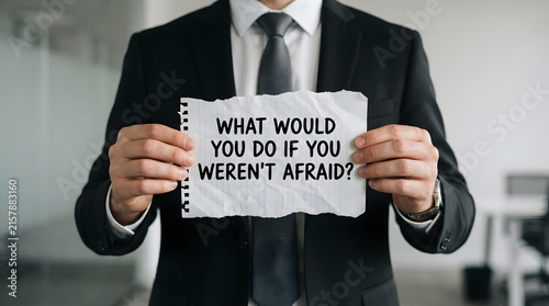Professional holding motivational question sign about overcoming fear in office setting with modern office environment motivational text asking