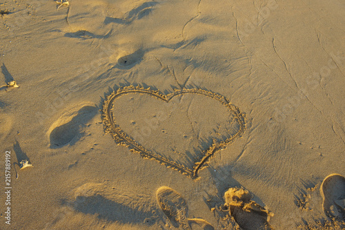 фотографія A heart drawn in the warm sand at sunrise, capturing a moment of love by the seaside