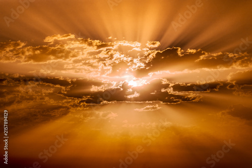 A dramatic sky with the sunrise breaking through the clouds and its distinct rays