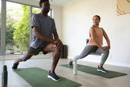 Obraz na płótnie African American couple lunging on green mats in workout clothes at home gym wit