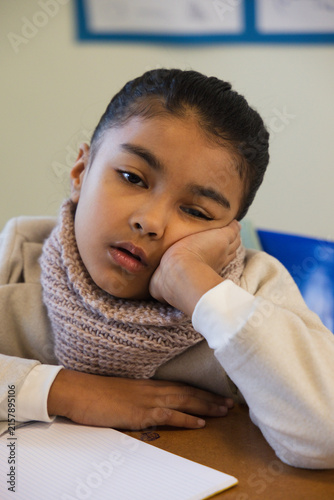 Canvas Print African American child sitting and resting on hand at desk in classroom with sca