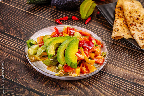 Photography Colorful avocado salad with bell peppers and grilled flatbread on wooden table