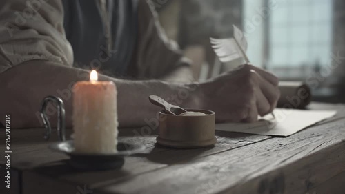 Wooden ink sander with a small scoop near a burning candle against the blurred background of a medieval inventor drawing a flying machine blueprint with a quill pen