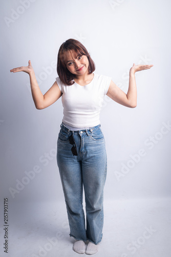 Smiling young woman shrugging with palms up on white background