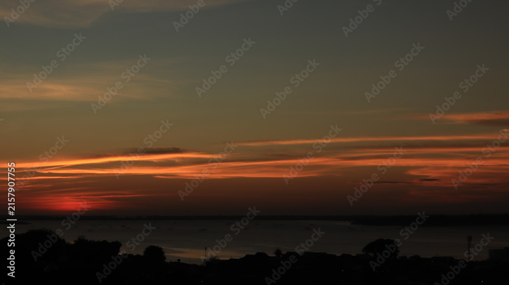 Fototapeta premium Low orange sunset in dramatic clouds over ocean 