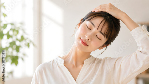自宅で首を伸ばしてリラックスする日本人女性のストレッチ・肩こり対策・健康管理イメージ