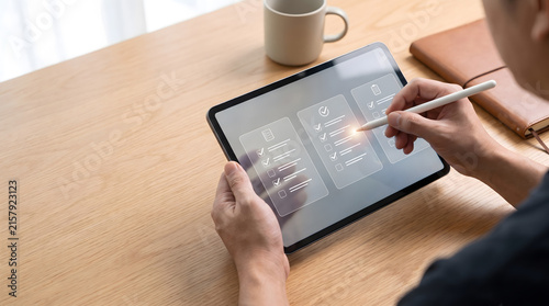 Person using stylus on tablet with virtual digital checklist and task management hologram, Digital document approval and online survey concept with glowing checkmarks on tablet screen.