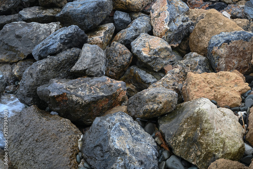 Картината върху платно Rocky coastline reveals textured stones and pebbles under soft sunset light by t
