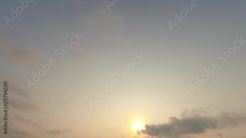 Serene time-lapse of a glowing sun in a hazy pale sky with a flock of birds flying past. A beautiful, peaceful atmospheric background for nature b-roll.