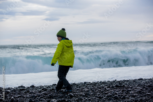 Child, playing on a beautiful beach in Snaefellsjokull National Park in Iceland, autumntime on sunset