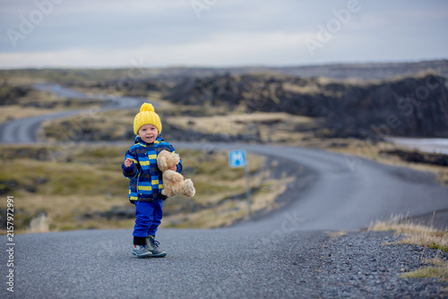 Child, walking on a curved road near ocean in beautiful nature in Snaefellsjokull National Park in Iceland, autumntime on sunset