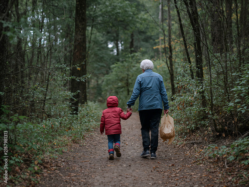 Senior woman and child walking hand in hand in forest