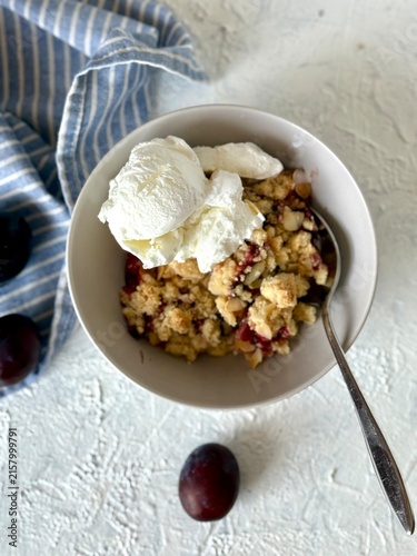 Fotografía Top view of hot plum crumble with melting ice cream and spoon in ceramic bowl