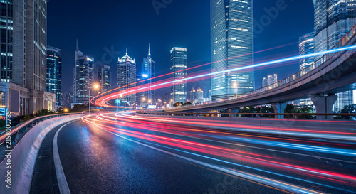 City skyline cityscape featuring urban highway traffic light trails at night with towering modern skyscrapers and bright glowing architecture in a busy metropolitan financial business district
