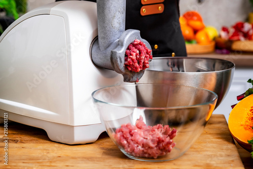 Konstfotografi Woman uses electric meat grinder, mincing raw pork into glass bowl