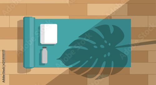Top view of yoga mat with towel and bottle on wooden floor with leaf shadow
