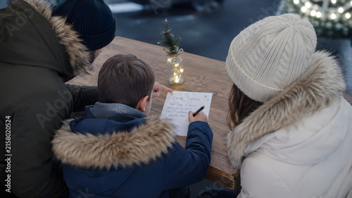 Family Writing Christmas Wish List Together at Holiday Market