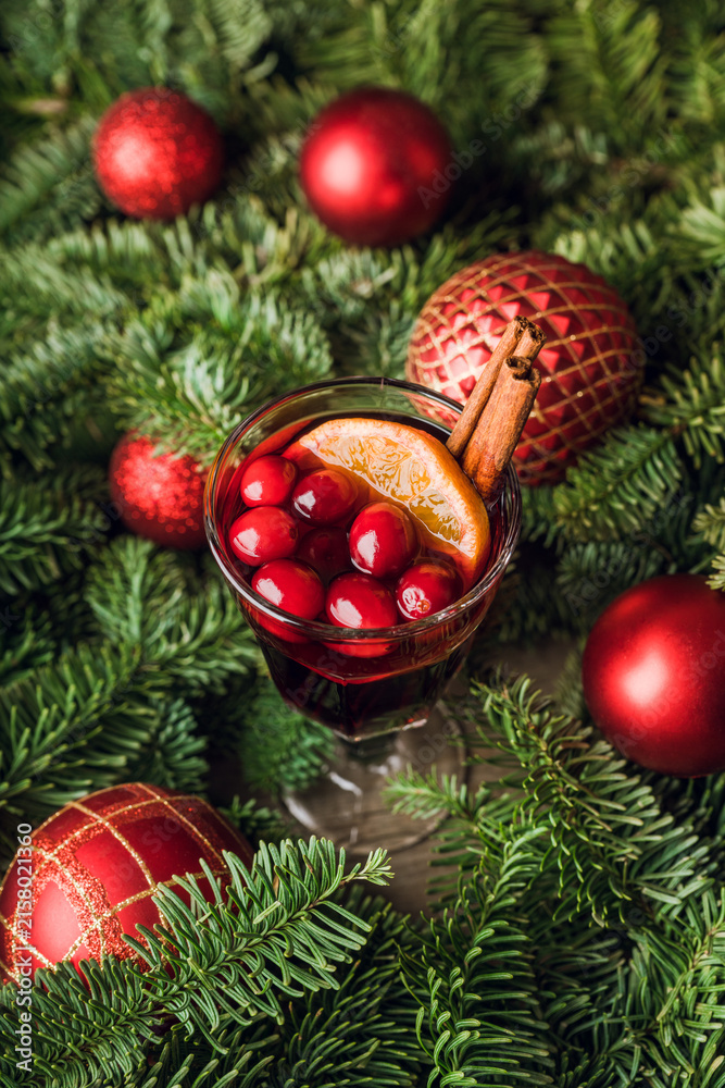 Fototapeta premium Mulled wine with orange, cranberry and cinnamon in fir forest setting. Selective focus.