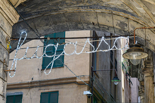 Fotografía Illuminated text sign fugassa (focaccia in dialect) under historic stone arches