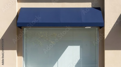 Dark blue fabric awning above a large glass window on a modern building exterior with sunlight and shadows.