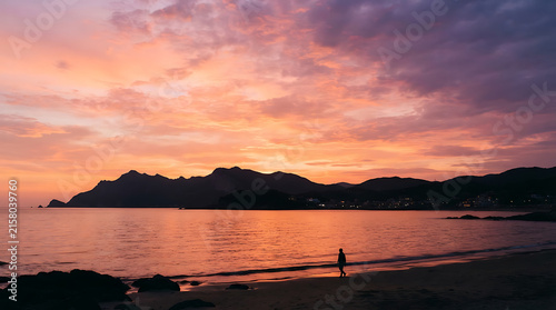 Serene sunset over calm lake with mountain silhouette