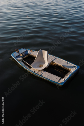 Old boat floating on calm water with a white seat inside