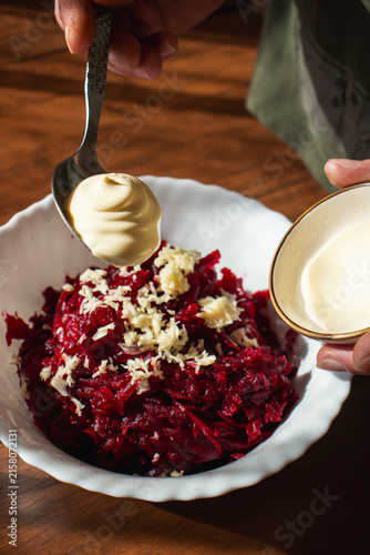 Bild auf Leinwand Adding Mayonnaise to Grated Beetroot and Garlic Salad